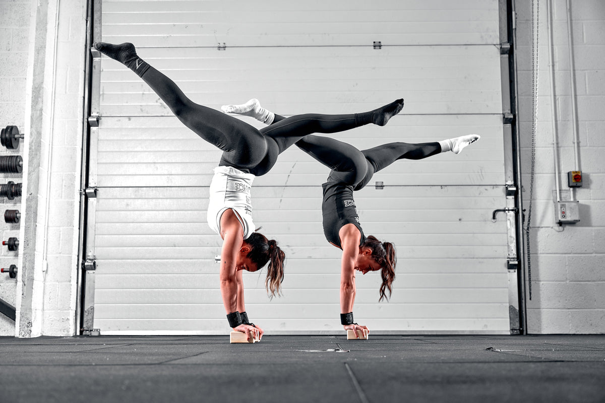 Two women doing handstands using balance addicts handstand blocks