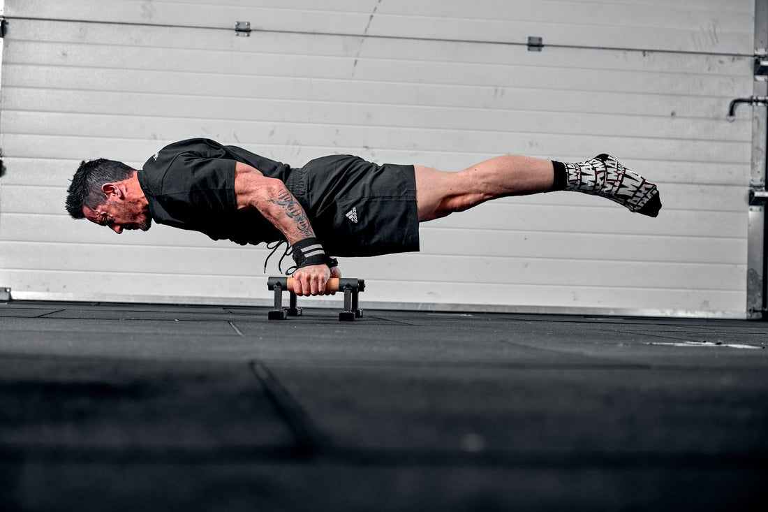 man balancing on parallette bars