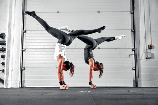 Two women doing handstands using balance addicts handstand blocks