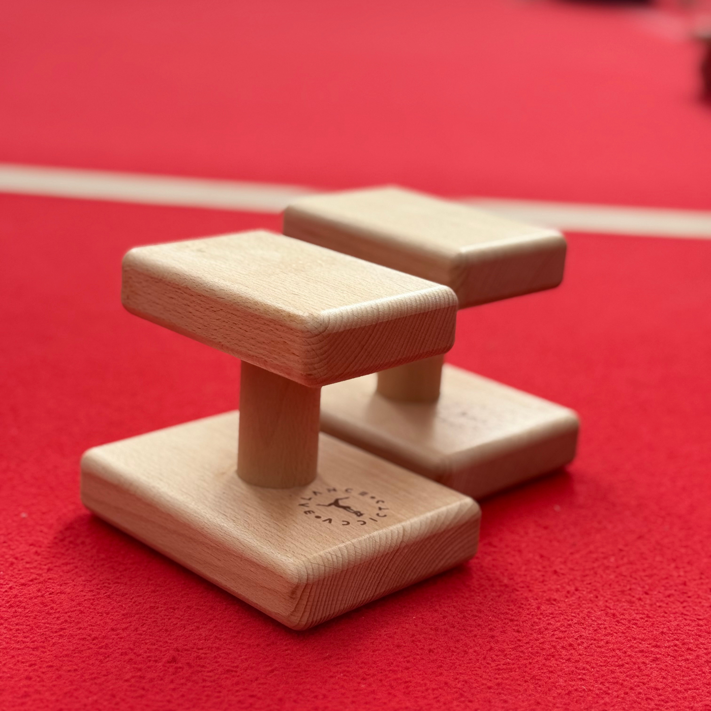 pair of raised handstand blocks on red gymnastics floor